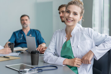 Obraz premium Young female doctor sitting and looking at camera during the meeting in hospital