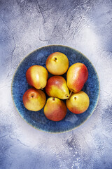 Sweet pears on textural, beautiful plate on blue background
