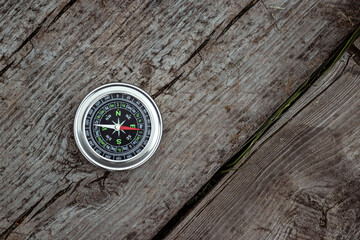 Fototapeta na wymiar Silver compass on a wooden background top view. The concept of travel, leadership, help. Copy space.