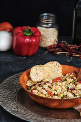 Vertical shot of a mexican traditional plate of esquites in a dark background