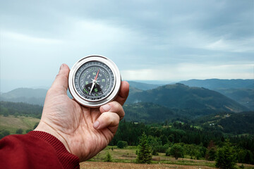 Compass in hand on a background of a landscape of mountains, Close-up. The concept of travel, hiking, vacation. Copy space.