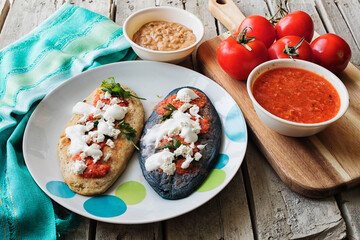 Prepared mexican traditional tlacoyos with red sauce and tomatoes on a wooden table