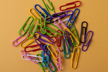 many colourful plastic paper clips on yellow