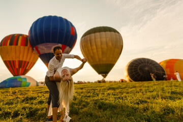 Beautiful romantic couple hugging at meadow. hot air balloon on a background