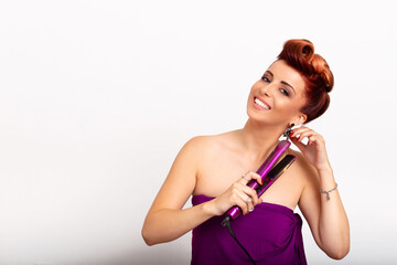 Young woman smiling while using hair straightener for her curly and well styled hair. Beautiful...