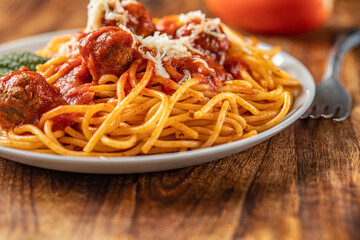 spaghetti dinner with meatballs and tomato sauce  arranged in a wooden background.