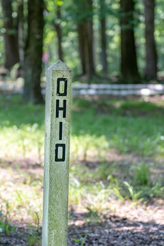 The name of the state Ohio engraved and painted black in a wood post painted white outside in a park