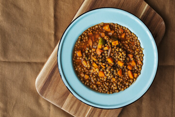 Lentils soup with vegetables on a blue plate (flat lay view)