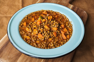 lose up of a blue plate of lentil soup with vegetables
