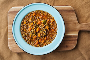 Overview of a lentil soup in a blue plate with vegetables