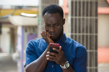 Close-up of a young man with mobile phone, thoughtful.