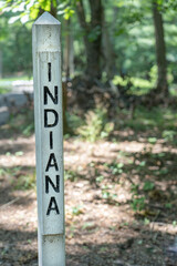 The name of the state Indiana engraved and painted black in a wood post painted white outside in a park