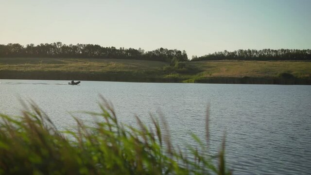 A man rides a motor boat in an inflatable boat on a lake at sunset. Fisherman rides a motor boat on the river.