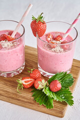 Strawberry milk shake in glass with straw and fresh berries on a white background