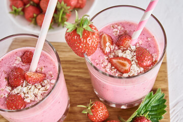 Strawberry milk shake in glass with straw and fresh berries on a white background