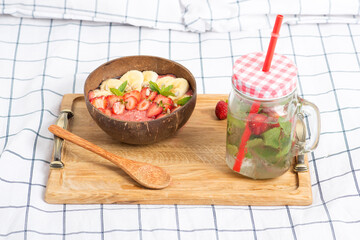 strawberry smoothie in a coconut bowl, water with strawberries, mint and ice, vegan breakfast in bed, wholesome food