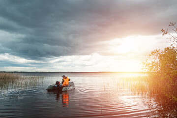 Grandson and grandfather together fish from a boat on the lake. The concept of family, summer vacation, generation. Copy space.