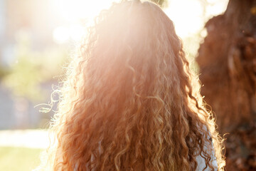 Portrait of a curly-haired girl in the setting sun.