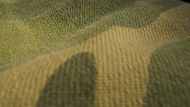 Extreme close up slide over camo patterned fabric.