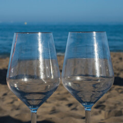 Dos copas de cristal vacías en la arena de la playa frente al mar