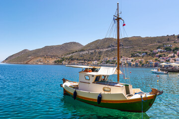 Naklejka na ściany i meble Boat anchoring in beautiful Symi bay with emerald green sea water. Symi island, Greece.