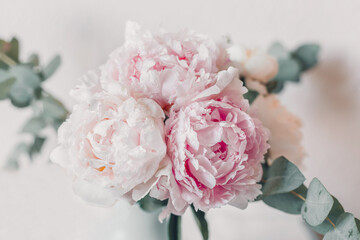 Delicate bouquet of peonies with eucalyptus branches in pastel colors selective focus