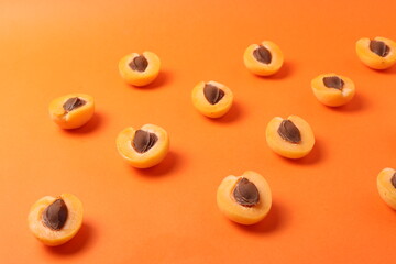 background pattern style shot of several orange ripen apricots with seeds on the bright orange color background
