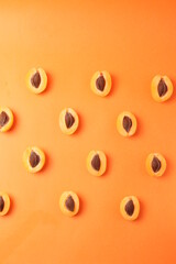 background pattern style shot of several orange ripen apricots with seeds on the bright orange color background