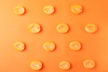 background pattern style shot of several orange ripen apricots with seeds on the bright orange color background
