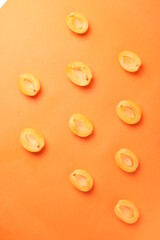 background pattern style shot of several orange ripen apricots with seeds on the bright orange color background