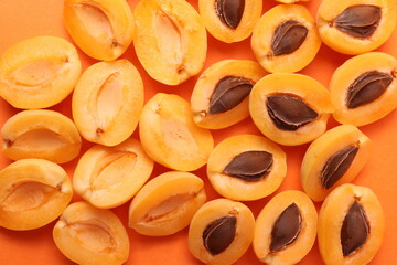 background pattern style shot of several orange ripen apricots with seeds on the bright orange color background