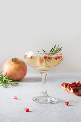 Sparkling wine, pomegranate, rosemary sprig on white table. Xmas drink.