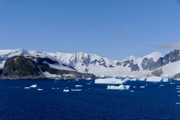 Iceberg in blue Antarctic sea, before mountains with blue sky, Antarctica