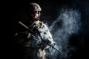 Naklejka premium portrait of a soldier in a military uniform with a weapon on a dark black background, a commando in military ammunition, the fight against terrorism