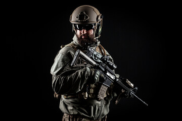 American commando in a military uniform with a weapon looks at copy space, a marine on a dark...