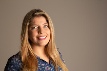 Portrait of young blonde woman smiling and looking at camera. Brazilian in neutral background. Happy and confident.