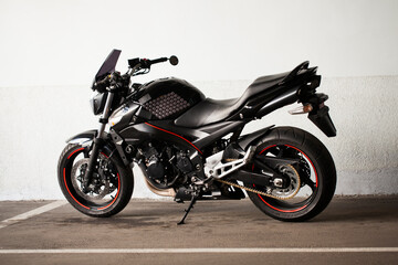 Sports black motorcycle on a background of an underground gray wall in the studio.