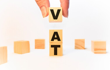 The text VAT ,value added tax, on wooden parts, a person holds on a white notebook