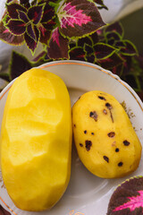 Big peeled new potatoes, yellow potatoes on a wooden board.