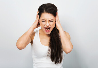 Angry casual woman strong screaming with wild open mouth and covering the ears the hands to not...