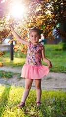 Portrait of pretty girl in pink dress in summer park