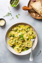 Ravioli with Pesto sauce and Parmesan Cheese on a light gray table. Traditional Italian pasta. Top view.