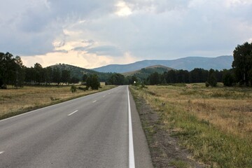 A road in the mountains going far beyond the horizon at sunset