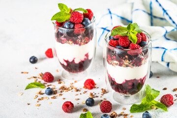Parfait with granola, jam and fresh berries in the glass jar.