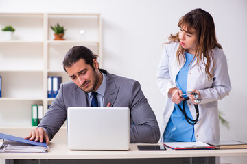 Fototapeta premium Young female doctor and sick businessman in the office