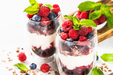 Parfait with granola, jam and fresh berries in the glass jar.