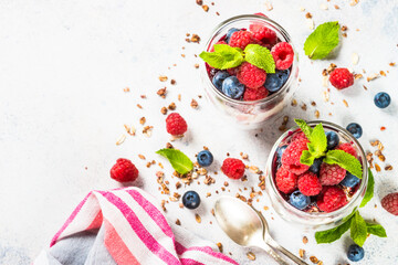 Parfait with granola, jam and fresh berries in the glass jar.
