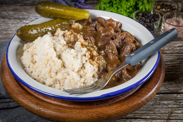 Beef stew served with barley and pickled cucumber.