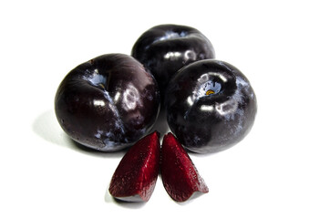 Three large red plums and two juicy slices of plum isolated on a white background. 