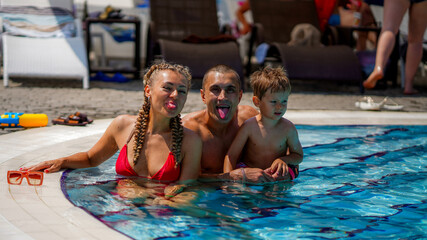 Obraz na płótnie Canvas Family on vacation. Mother, athletic father and little boy in water park